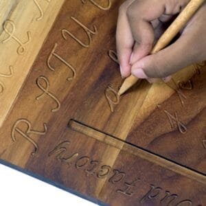 Child practicing handwriting on a wooden tracing board