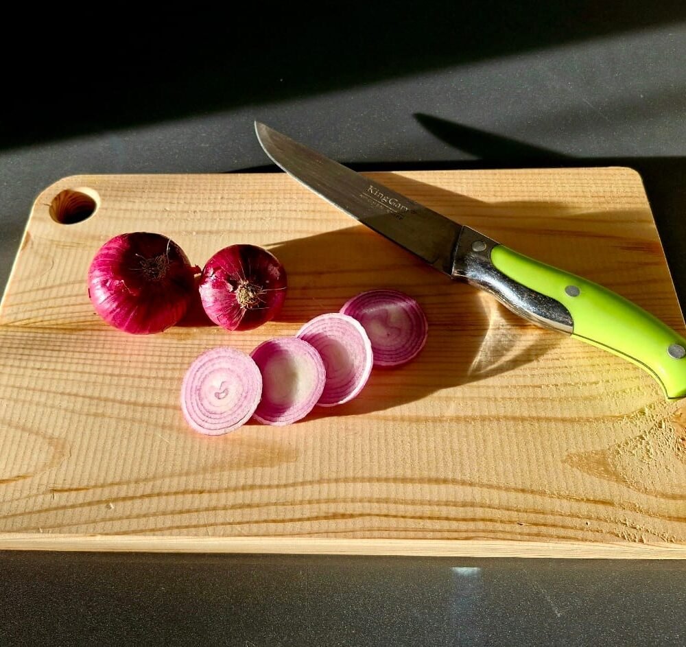 Pine wood chopping board with fresh vegetables and a chef’s knife